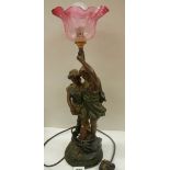 A bronzed effect figure group table lamp with cranberry glass shade.