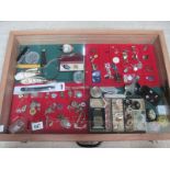 A display case containing assorted jewellery, trinket boxes, badges etc.
