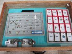 A display case containing in excess of 50 silver rings and 2 gent's wrist watches.