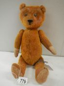 A straw filled Teddy bear, 15" long, in fair condition.