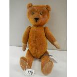 A straw filled Teddy bear, 15" long, in fair condition.