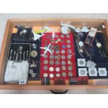 A display case containing silver chains, assorted coins, model aircraft, watches, cloth badges etc.