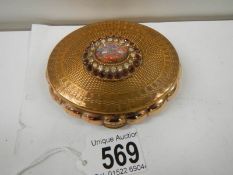 A 1950's oval powder compact with jeweled top, in good condition.