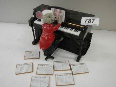 A battery operated mouse playing a piano with 7 tune sheets that are inserted in the back for him