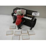 A battery operated mouse playing a piano with 7 tune sheets that are inserted in the back for him