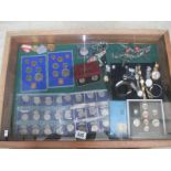 A display case containing miscellaneous coins, watches, medals etc.