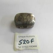 An engraved silver pill box.