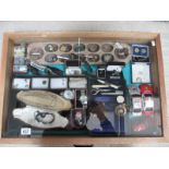 A display case containing assorted jewellery, watches, model cars etc.
