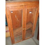 A Pine wall cabinet with glass door.