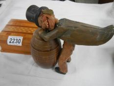 An unusual wooden cigarette dispenser being a man leaning on a barrel.