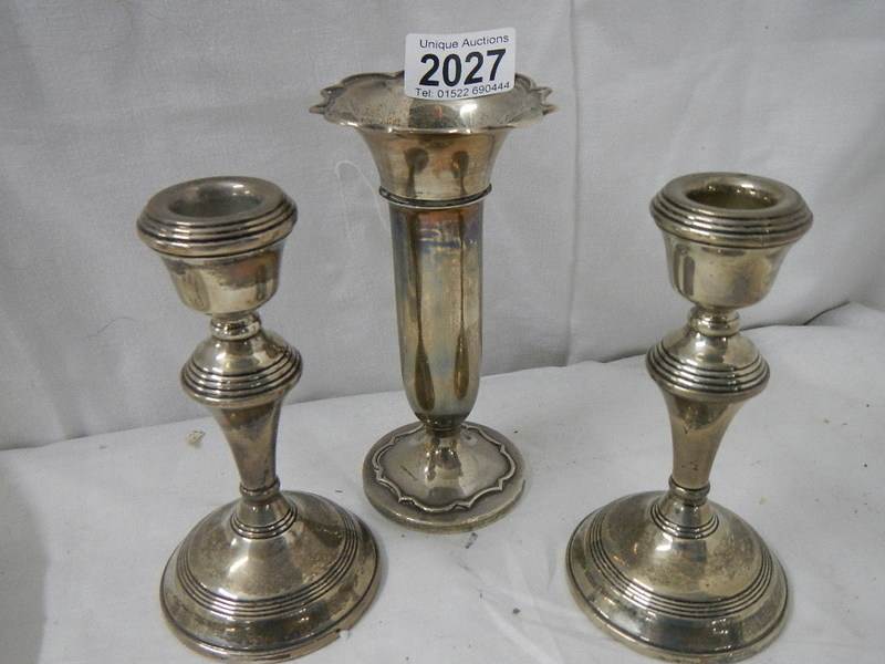 A pair of silver candlesticks and a silver spill vase.