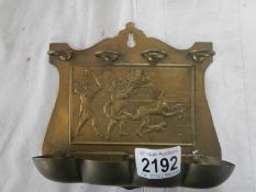 A brass pipe rack with embossed jesters on back.