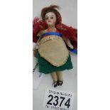 A miniature porcelain doll, three and three quarter inches tall.