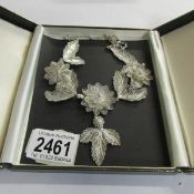 A vintage silver filigree necklace fashioned with flowers and leaves, attached pendant drop,