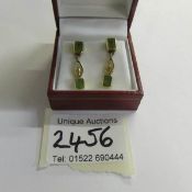 A pair of 14ct gold peridot drop earrings set with emerald cut peridots and pierced setting,