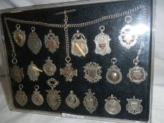 A collection of 20 silver watch fobs with chain.