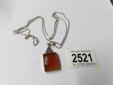 An amber pendant on silver chain,.