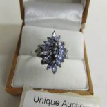 A tanzanite and diamond ring cluster setting in silver, size O.