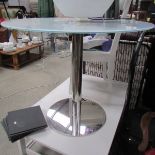 A chrome based circular table with white glass top.