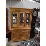 A light wood display cabinet with cupboard base