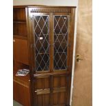 A drak oak corner cupboard with leaded glass doors