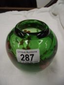 A heavy green art glass vase decorated with flowers