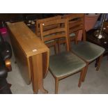 An oval drop leaf table (teak effect) and 4 dining chairs