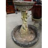 A bird bath with cherub base.