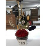 A hat pin stand with assortment of hat pins.