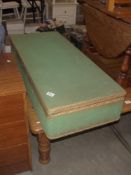 A green Lloyd Loom type long low under-bed blanket box
