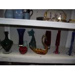A shelf of art coloured glass etc.