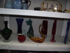 A shelf of art coloured glass etc.