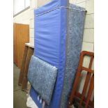 A mottled blue single bed base with matching head board and protected mattress