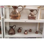 A set of seven graduated copper ale jugs