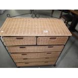 A wicker and wrought iron bathroom chest of drawers.