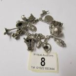 A silver charm bracelet with 15 interesting charms, four open, a boxing glove, vintage car,