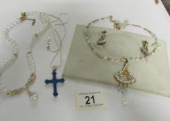 A necklace with matching earrings, a cross on chain and a pearl necklace.