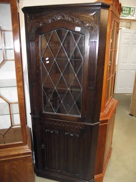 A dark oak linen fold lead glazed corner cabinet.