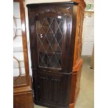A dark oak linen fold lead glazed corner cabinet.
