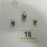 A silver skull pendant and matching earrings with ruby eyes.