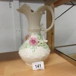 A Belleek jug decorated with applied roses, 23 cm tall.