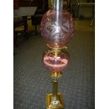 A Brass Corinthian column oil lamp with cranberry cut glass font and shade.