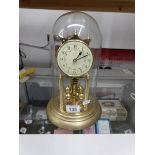A brass anniversary clock under glass dome.