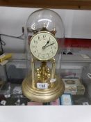 A brass anniversary clock under glass dome.