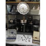 4 shelves of assorted chrome and silver plate including cutlery, tray, condiment sets etc.