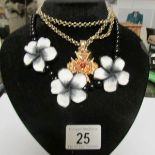 A black and white necklace together with another necklace on stand.