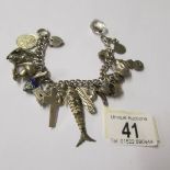 A vintage charm bracelet with a variety of mostly silver charms, some opening, one for Chester,