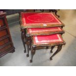 A mahogany nest of tables with red leather inset tops