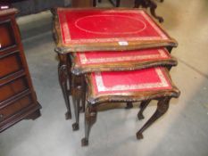 A mahogany nest of tables with red leather inset tops