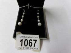A pair of white gold and graduated pearl drop earrings.